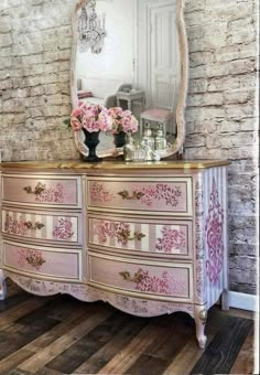 an antique dresser with pink flowers on it and a large mirror over the top of it