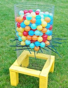 a basket filled with lots of balls sitting on top of a grass covered field next to a wooden bench