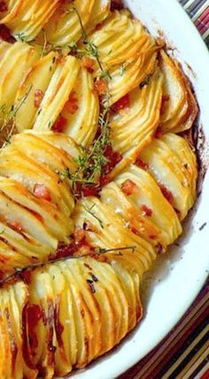 baked potato dish with herbs and seasoning in a white bowl on a striped tablecloth