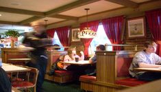 people sitting at tables in a restaurant with red curtains