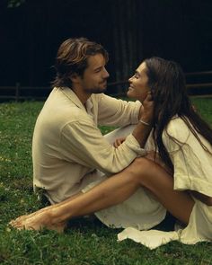 a man and woman sitting on the grass together