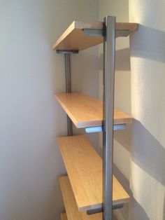 an empty room with wooden shelves and metal bars on the bottom floor, in front of a white wall