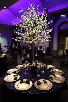 the table is set with black and white plates, silverware, and a centerpiece