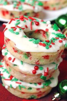 a stack of cookies with white frosting and sprinkles next to christmas decorations