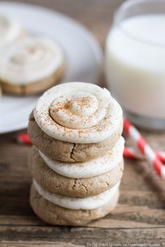 a stack of cookies sitting on top of a wooden table next to a glass of milk