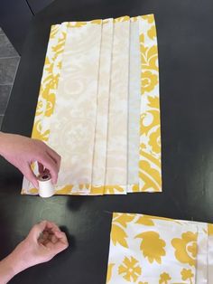 someone is painting yellow and white fabric on the table