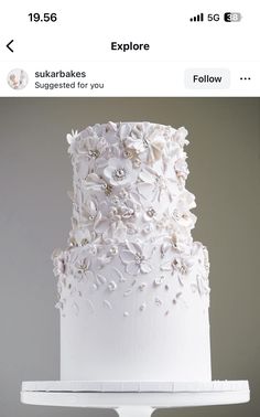 a white wedding cake with flowers on the top is displayed for an instagramr