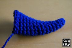 a crocheted blue object is sitting on the table next to it's string