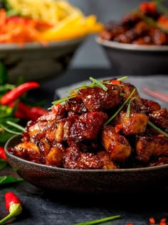 a bowl filled with meat and vegetables on top of a table next to other bowls