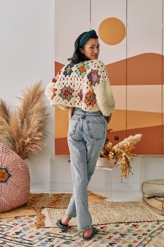 a woman standing in front of a wall wearing an oversize sweater and high waist jeans