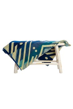 a chair with a blue and white blanket on it's back, in front of a white background