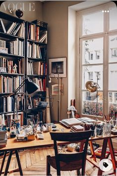 a room filled with lots of books next to a desk and chair in front of a window