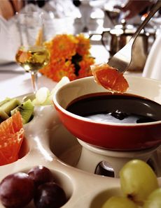 there is a bowl of soup with grapes and oranges on the table next to it