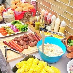 an assortment of food is displayed on a picnic table with hotdogs, cornbreads and other foods