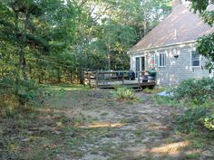 a house in the woods with trees around it and a deck on the front porch