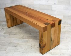 a wooden bench sitting on top of a tile floor next to a white brick wall