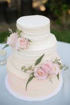 a white wedding cake with pink flowers and greenery