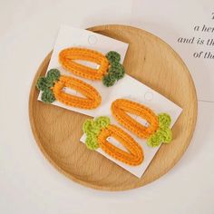 two crocheted broochies with leaves on them sitting on top of a wooden plate