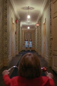 two girls in red shirts are walking down a hallway with mirrors on the wall behind them