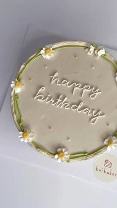 a birthday cake with the words happy birthday written in white frosting on it and daisies