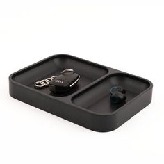 a black tray with two compartments holding ear buds and a pair of scissors in it