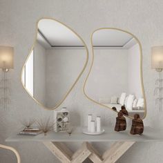 a white table topped with two mirrors next to a vase and candle on top of it