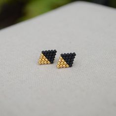 Satin 24kt Gold Plated and Matte Black Glass Seed Beads This beautiful pair of diamond-shaped stud earrings is a lovely way to add simplicity to your wardrobe, or give as a gift. Each earring has 25 Japanese Miyuki Delica beads expertly handwoven together into a minimalist diamond shape by needle and strong nylon thread. Each delicate earring is attached to a 14kt gold filled ear post with matching back. The size of each diamond is 11 mm tall by 8 mm wide. Delicate Earring, Beaded Jewelry Earrings, Stitch Earrings, Bead Loom Designs, Miyuki Delica Beads, Brick Stitch Earrings, Bead Weaving Patterns, Beaded Earrings Patterns, Delica Beads