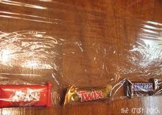 three candy bars wrapped in plastic sitting on a wooden table top next to each other