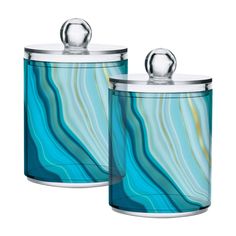 two blue glass canisters with metal lids and silver handles, one has a marbled design on the lid