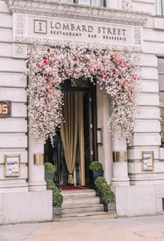 an entrance to a restaurant with pink flowers hanging over the door and steps leading up to it