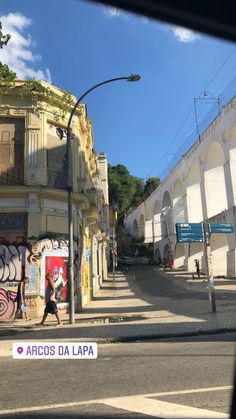 a person walking down the street in front of some buildings with graffiti on them and a sign that says arcos da lapa