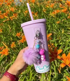 a person holding up a cup with charms on it