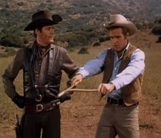 two men in cowboy hats are pulling something with one hand and another holding the other