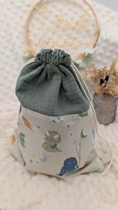 a small bag sitting on top of a bed next to a vase with flowers in it