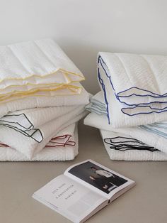 a stack of folded towels sitting on top of a table next to an open book