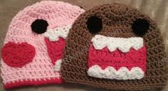 two crocheted hats are sitting on a bed