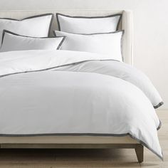 a bed with white sheets and pillows in a room