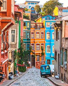 a car parked on the side of a cobblestone road in front of colorful buildings