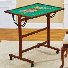 a small wooden table with a green top on casteors and wheels in a living room