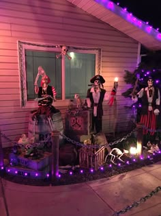 a house decorated for halloween with skeletons and other decorations on the front porch at night