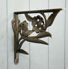 a metal wall hanging with flowers and leaves on it's side, in front of a white door