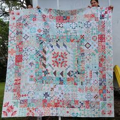 a woman is holding up a quilt made from scrap material