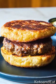 two hamburger patties on a blue plate with a side of ranch dressing in a small bowl