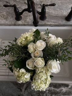 a bouquet of white flowers sitting on top of a sink