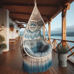 a hanging chair on a wooden deck next to the ocean with potted plants in it