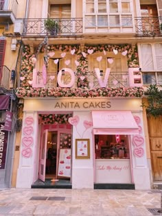 a pink store front with flowers and hearts on the outside, along with an awning that says love