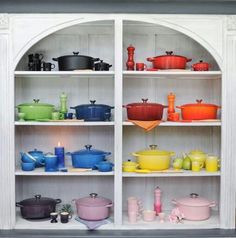 the shelves are filled with colorful pots and pans