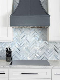 a stove top oven sitting inside of a kitchen next to white cabinets and counter tops