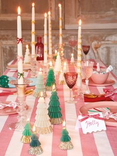 a table set for christmas with candles and place cards on the plates, napkins and glasses