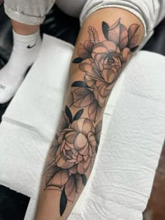 a woman's arm with flowers and leaves on the top half of her leg